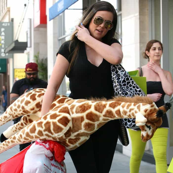 Khloe Kardashian holding a plush giraffe