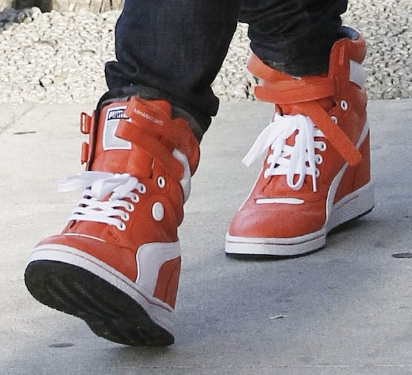 Gwen's orange wedge sneakers from Puma adding color to her ensemble
