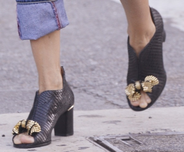 Sarah Jessica Parker wearing shoes featuring an allover reptilian embossing with thick heels and gold bow detail above the peep toes
