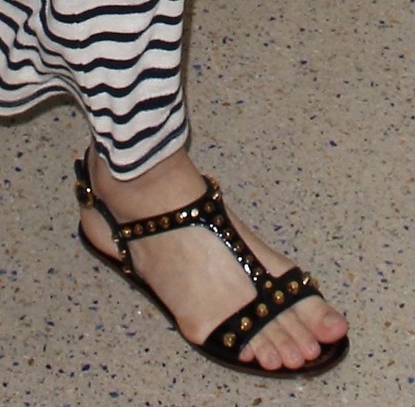 Miranda Kerr wearing Prada sandals featuring patent ankle straps and t-straps that are embellished with brass-toned studs