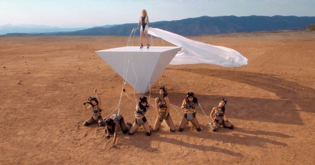 Britney Spears wearing tasseled ankle-strap heels for a bondage scene in the desert