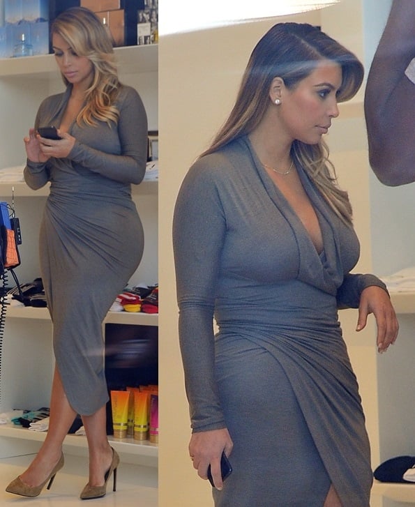 Kim Kardashian flaunting her curves in a fitted gray long-sleeved wrap dress with a plunging neckline