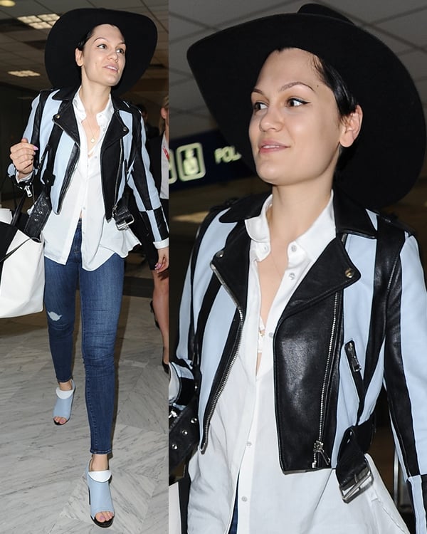 Jessie J in a white top, a pair of denims, a black wide-brimmed hat, a blue-and-black leather jacket, and matching peep-toe booties with fold-over detail by Balenciaga
