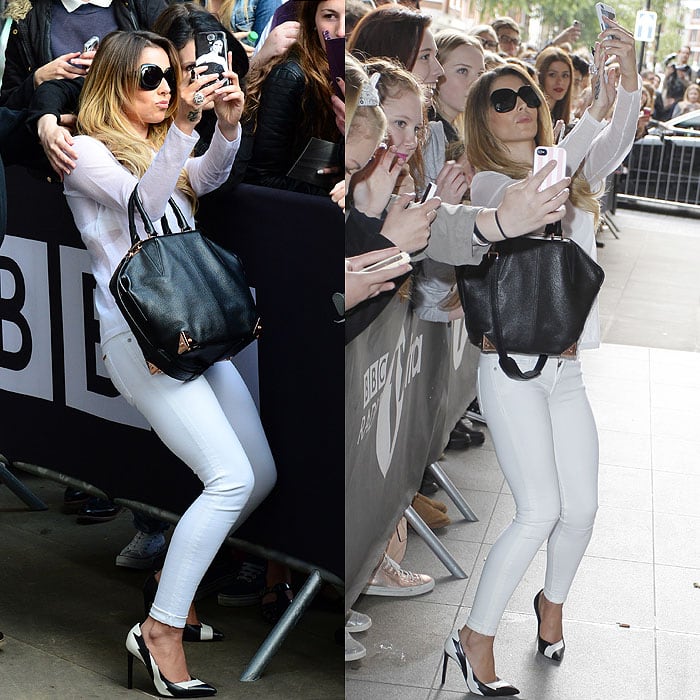 Cheryl Cole crouching to take pictures with fans