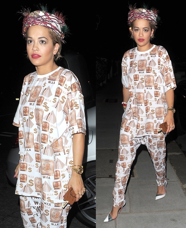 Rita Ora wearing a baggy W.I.A. Collections outfit that features an Egyptian-themed print made up of pyramids, hieroglyphs, and dollar signs