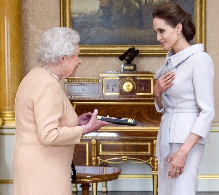 Actress Angelina Jolie presented with the Insignia of an Honorary Dame Grand Cross of the Most Distinguished Order of St Michael and St George by Queen Elizabeth II in the 1844 Room at Buckingham Palace for services to UK foreign policy and the campaign to end war-zone sexual violence. In London, England, on October 10, 2014.