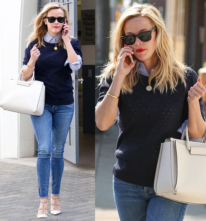 Reese Witherspoon wearing a cool-chic ensemble consisting of a navy sweater, a light blue button-down blouse underneath, and a pair of skinny jeans