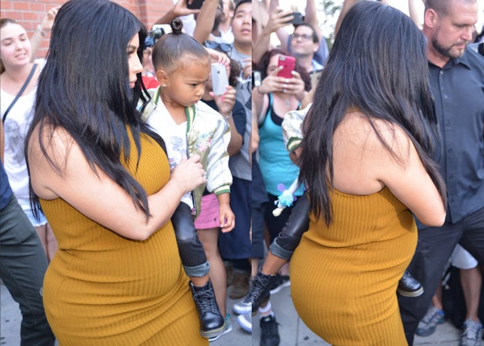 Kim Kardashian shows off her growing baby bump in a mustard-colored dress by Laquan Smith