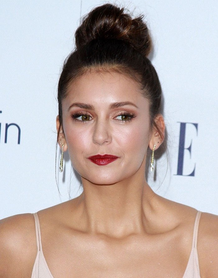 Nina Dobrev's hair was swept up into a high bun, while her face was gorgeously made up with a slick of red lipstick