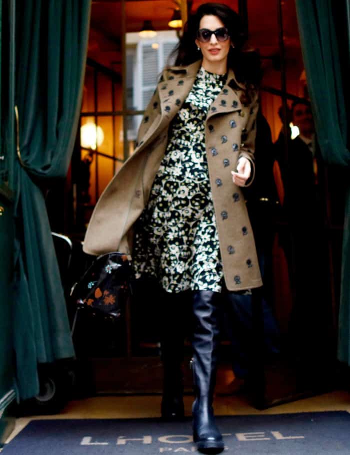 Amal Clooney wearing a monochromatic floral dress, a patterned trench coat, and over-the-knee boots in Paris