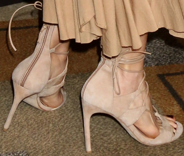 The actress wears a youthful pair of Stuart Weitzman "Legwrap" sandal in nude suede