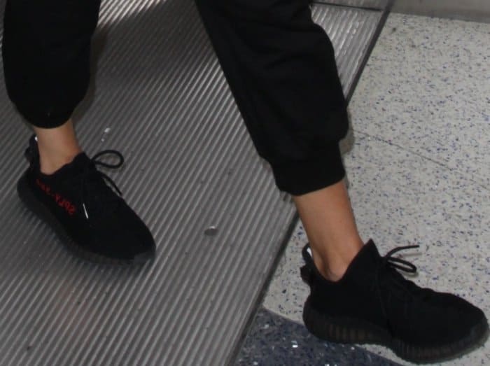 Khloe Kardashian wearing an all-black outfit styled with Yeezy Boost 350 V2 Sneakers at LAX