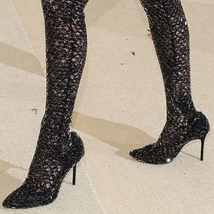Bella's black pointy-toe pumps are covered by her beaded catsuit