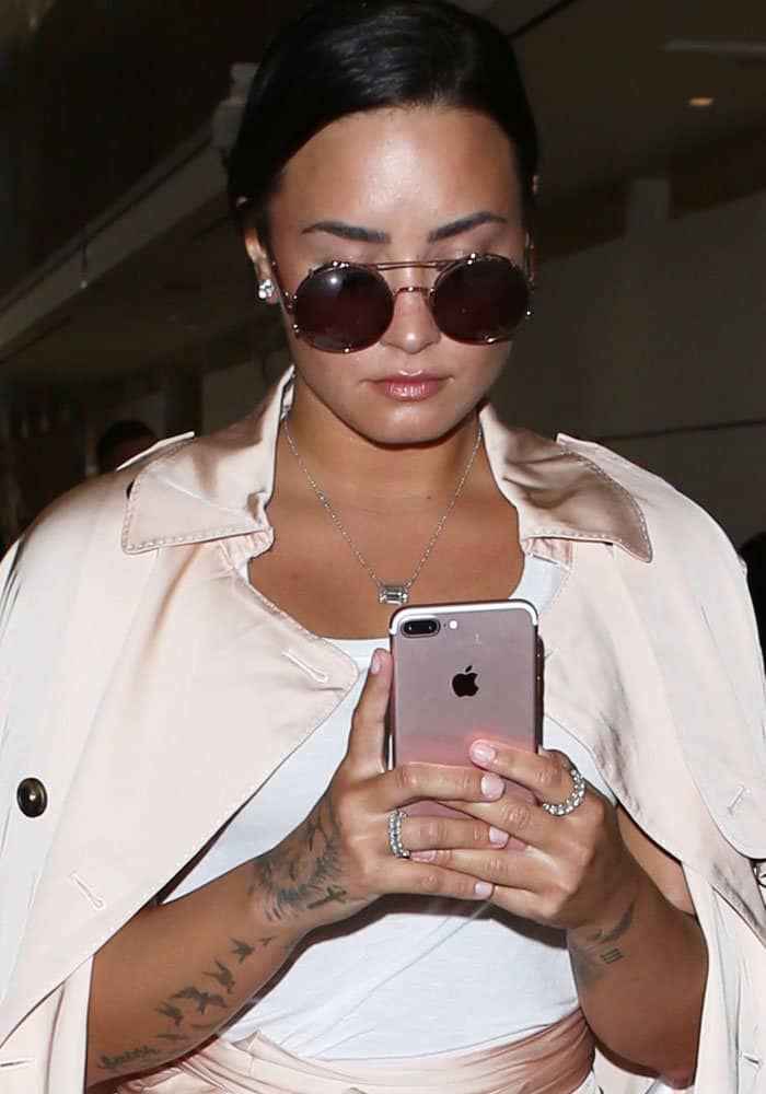 Demi attends to her phone as the camera flashes go off