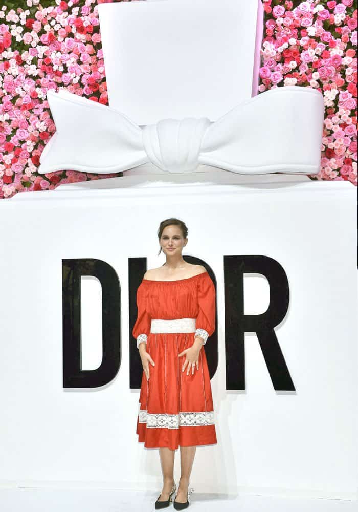 Natalie stands in front of the flower-laden Dior signage for the cameras
