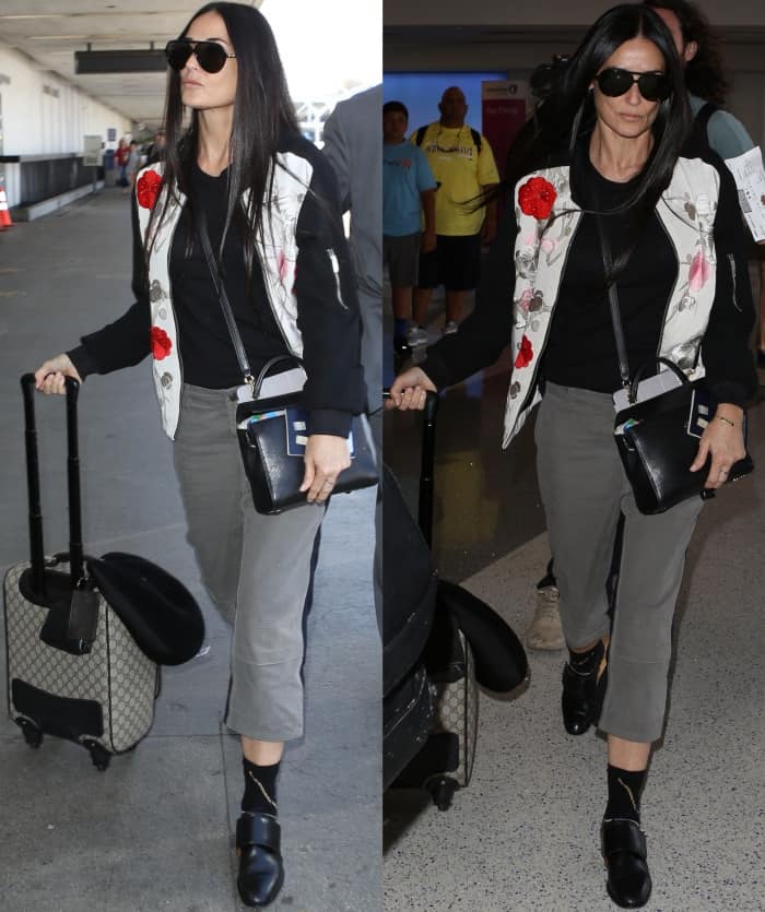 Demi Moore arriving at LAX in a floral-embroidered bomber jacket, grey pants, and black leather slip-on shoes