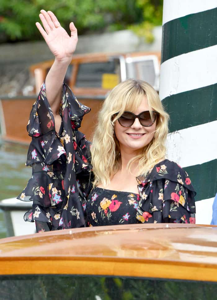 Kirsten waves to the cameras as she arrives at the port