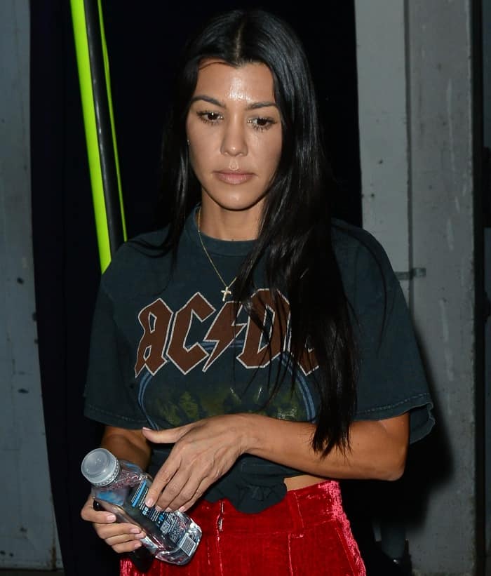 Kourtney Kardashian wearing a vintage AC/DC shirt and AOTC red velvet trousers while leaving a church service in Beverly Hills