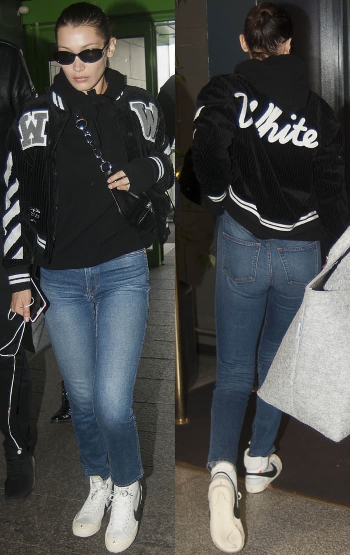 Bella Hadid wearing an Off-White c/o Virgil Abloh cotton corduroy crop varsity jacket, denim jeans, and Off-White for Nike "Blazer Mid" sneakers at the Milan-Malpensa Airport
