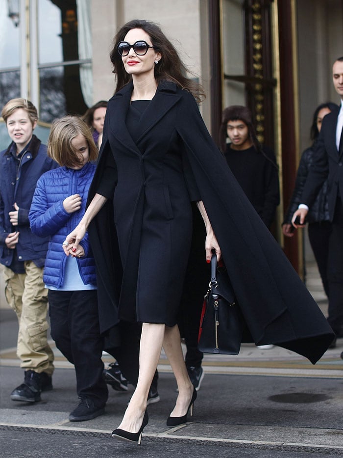 Angelina Jolie cut a stylish figure in an Elie Saab caped coat, a Salvatore Ferragamo large top-handle bag, and her trusty Fendi sunglasses