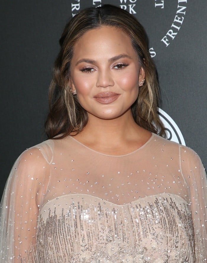 Chrissy Teigen in a champagne-colored feathered Pamella Roland Spring 2018 cape gown
