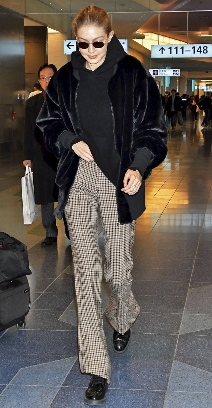 Gigi Hadid wearing patterned bell-bottom pants paired with a 'Teddy' stretch cotton-trimmed faux shearling bomber jacket from House of Fluff at Tokyo International Airport on January 26, 2018
