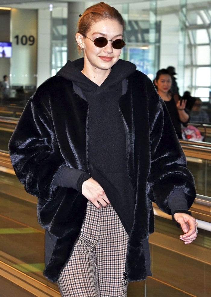 Gigi Hadid wearing patterned bell-bottom pants paired with a 'Teddy' stretch cotton-trimmed faux shearling bomber jacket from House of Fluff at Tokyo International Airport on January 26, 2018