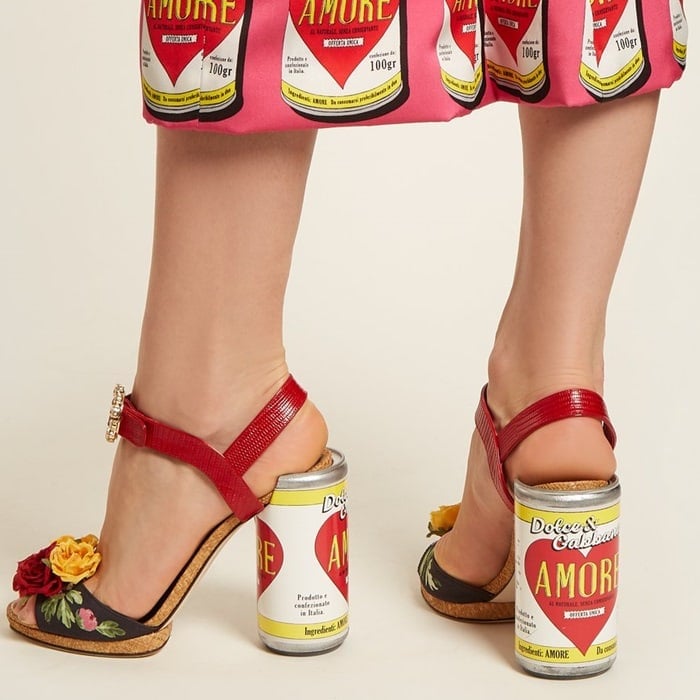 They're crafted in Italy with roses and crystal embellishments across the front strap and set on a cylindrical heel styled with a yellow, white, and red 'Amore’ can motif