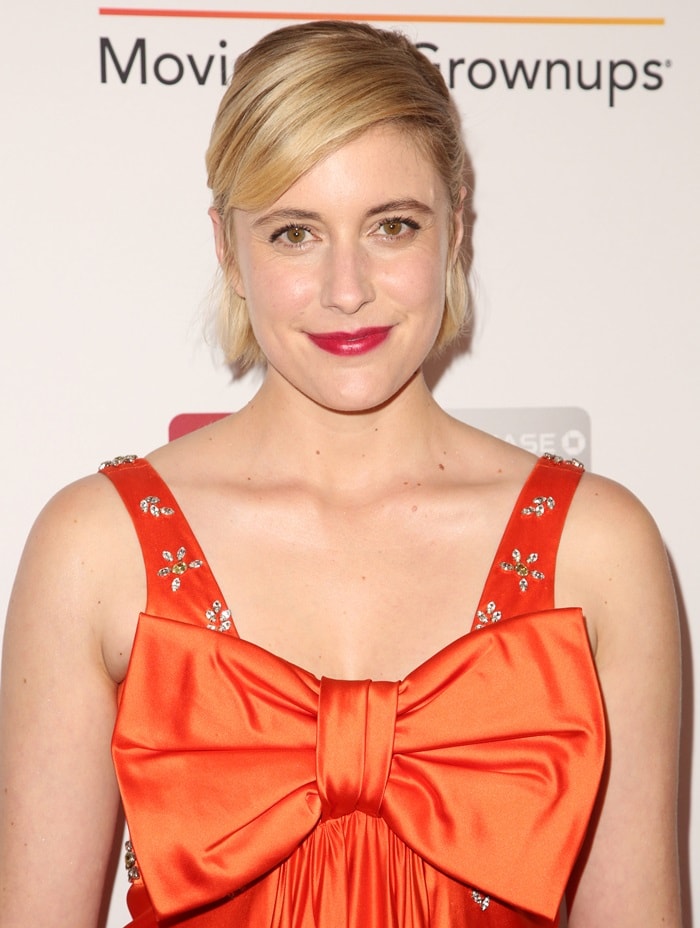 Greta Gerwig in a tangerine-colored vintage Cardinali dress featuring an oversized bow