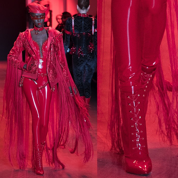 A model wearing a red latex jumpsuit with a long-fringed jacket and Christian Louboutin for The Blonds red patent lace-up booties.