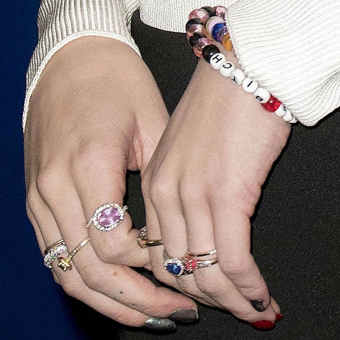 Details of Bella Thorne's rings, chipped red-and-silver nail polish, and "BITCH" bead bracelet.