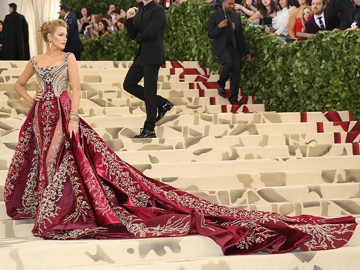 Blake Lively posing in her Atelier Versace wine red and gold gown at the 2018 Met Gala.