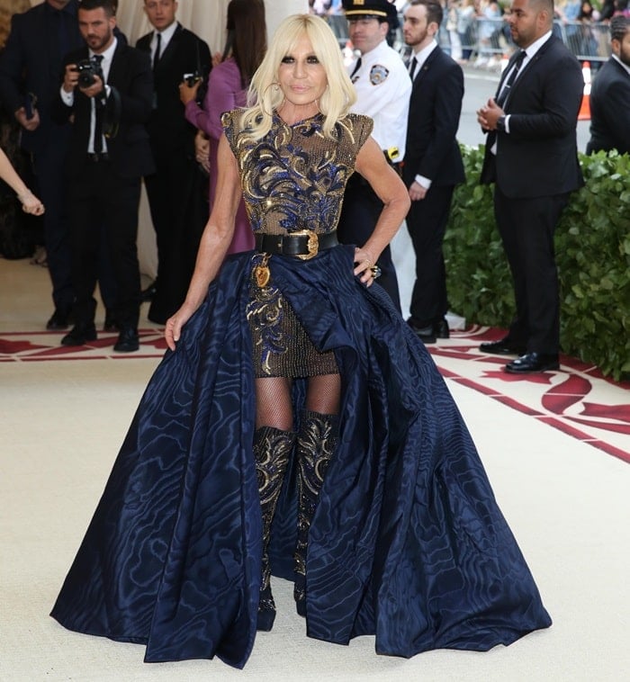 Donatella Versace in an embroidered mini dress styled with matching knee boots and a black belt