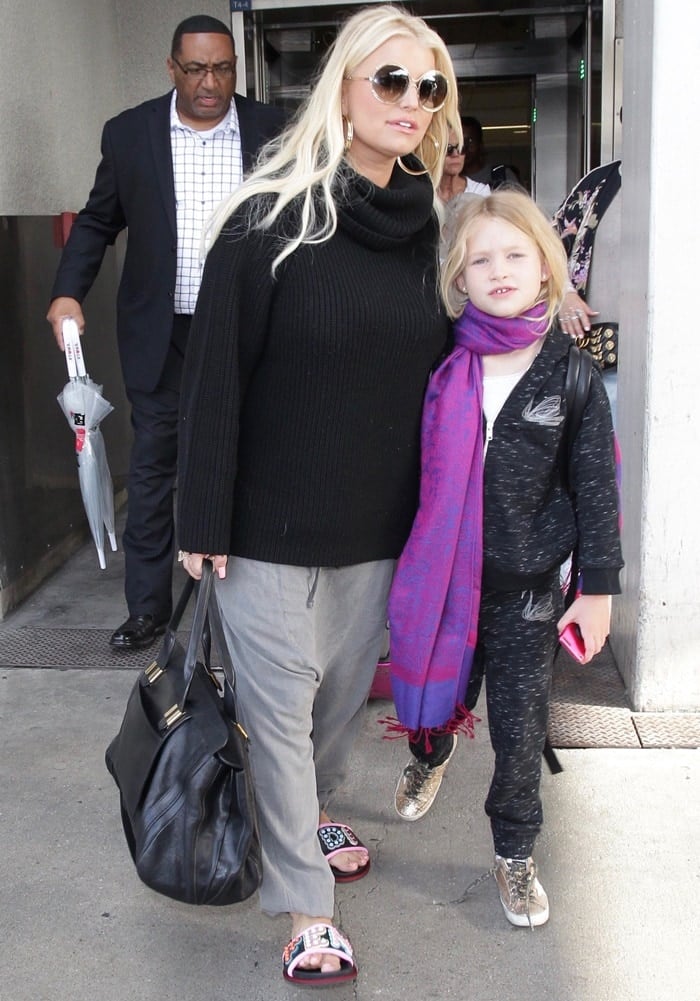 Jessica Simpson in sweatpants, a comfy black sweater, and studded logo slide sandals from Fendi