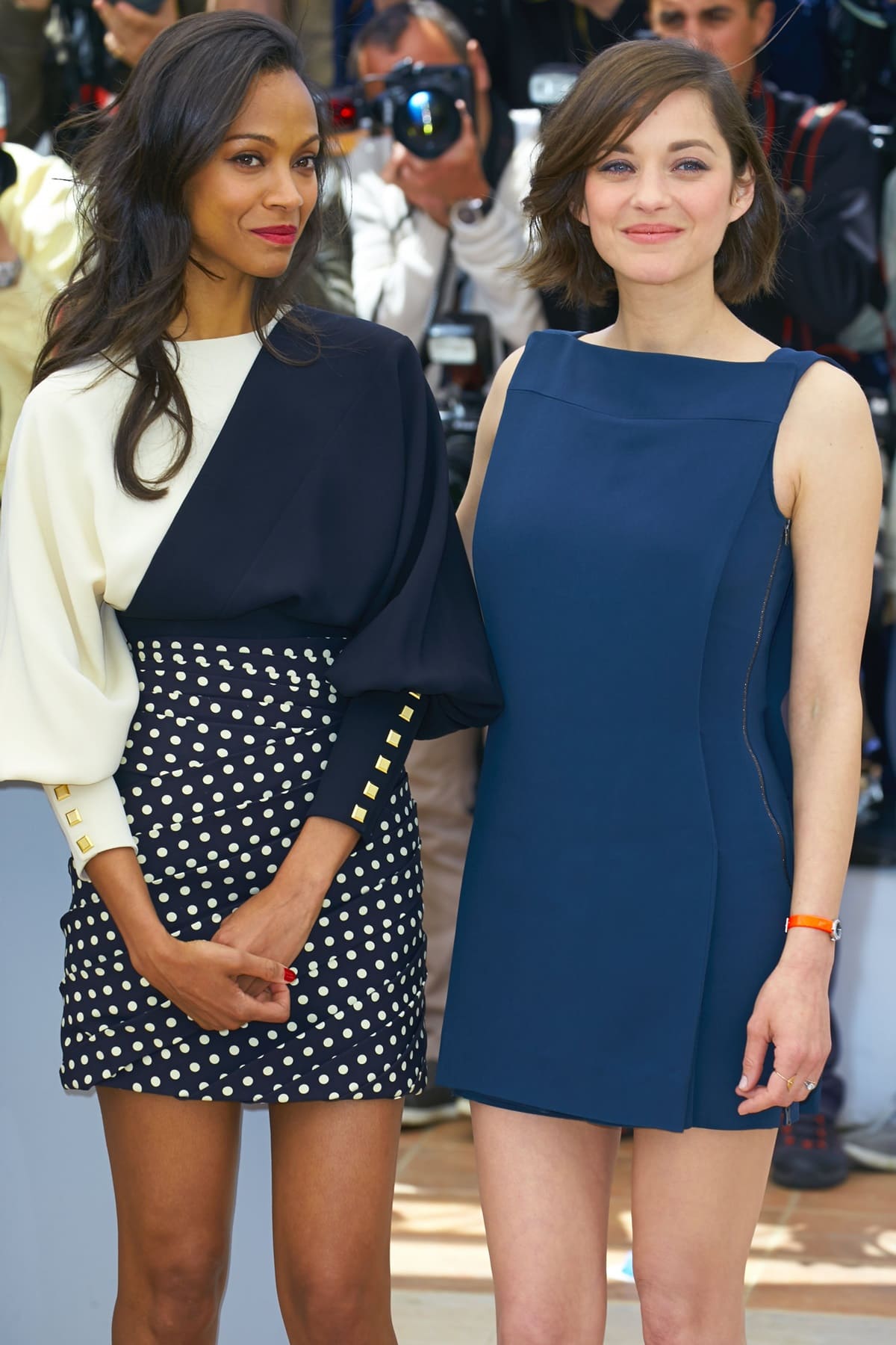 Zoe Saldaña stuns in a chic polka-dot mini skirt with a dramatic two-tone blouse, while Marion Cotillard exudes elegance in a sleek navy asymmetrical dress