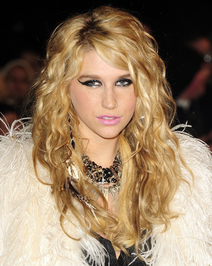 Kesha showcases her vibrant makeup with false lashes and bubblegum pink lips at a London event