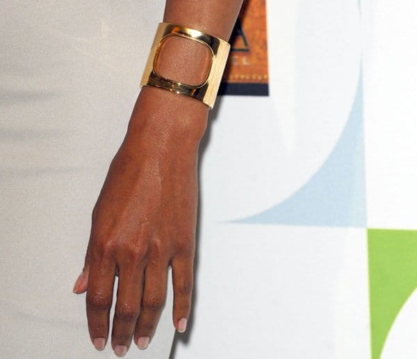 Accessorizing with finesse: Halle Berry showcases her stylish gold cuff bracelet, complementing her chic grey ensemble