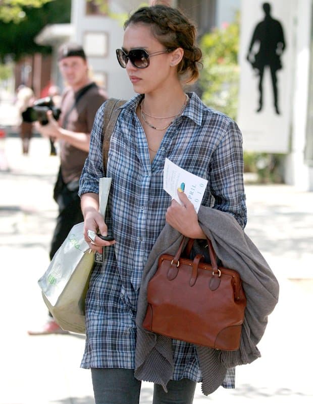 Captured on April 13, 2010, Jessica Alba stylishly exits an office building in Brentwood, effortlessly balancing multiple items in her hands, showcasing her multitasking prowess