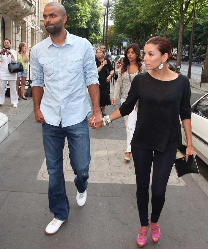 Eva Longoria turns heads in a casual all-black ensemble, adding a vibrant pop of color with bold fuchsia platform sandals as she strolls hand in hand with Tony Parker