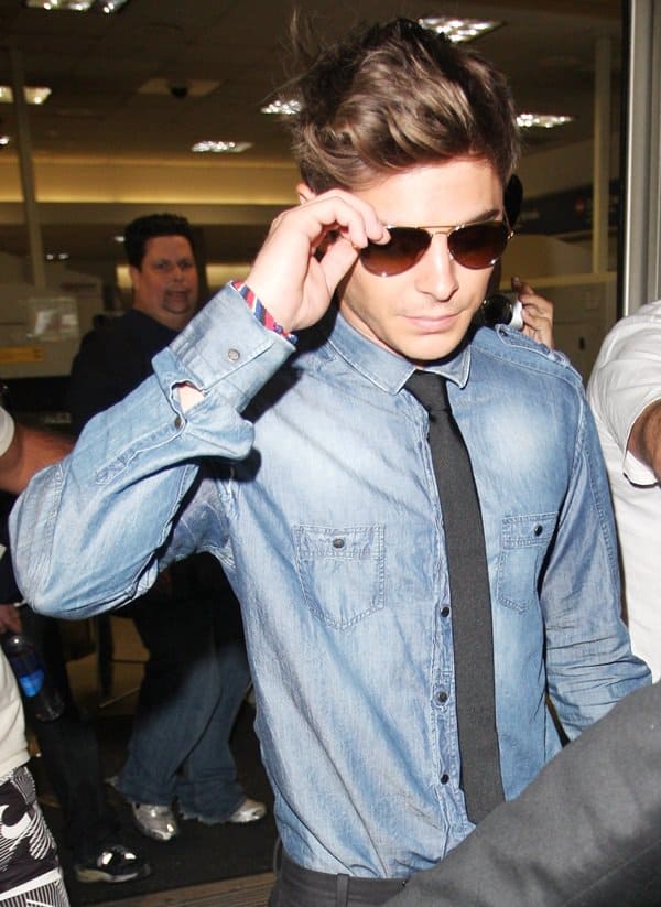 Zac Efron can make a shiny denim shirt work for traveling