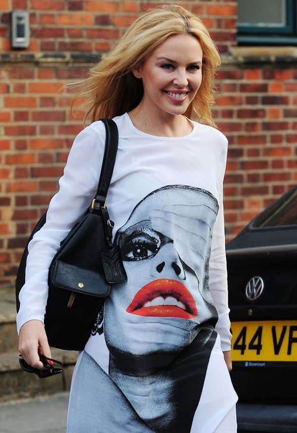 Kylie Minogue showcases her bold fashion sense in a striking Richard Nicoll face-print dress, paired with a sleek black bag, as she steps out in London on September 22, 2010, following a meeting at her management company's headquarters