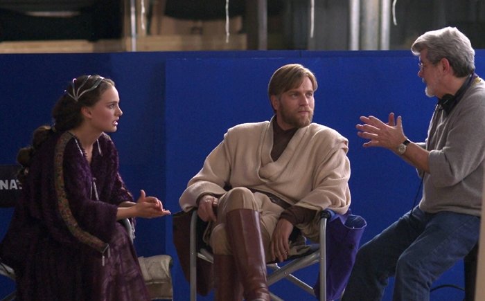Natalie Portman (Senator Padme Amidala) and Ewan McGregor (Obi-Wan Kenobi) listen to director George Lucas describe the next shot on the set of Star Wars: Episode III Revenge of the Sith