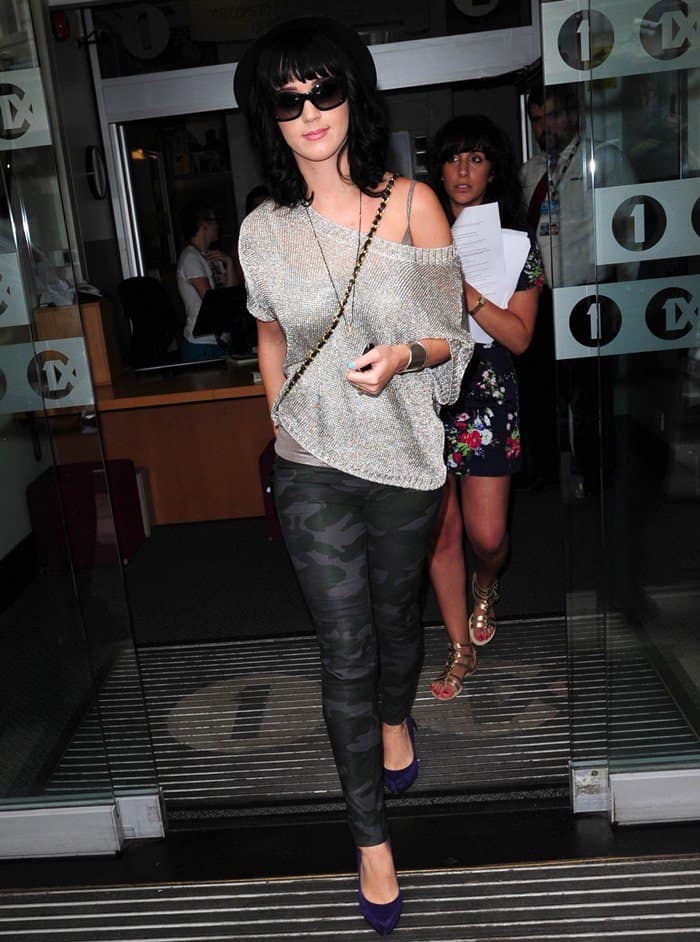 Katy Perry at the Radio One studios in London, June 24, 2010, showcasing her unique fashion sense in camouflage leggings, a glittery metallic sweater by Vince, and striking purple suede pumps by Rock & Republic