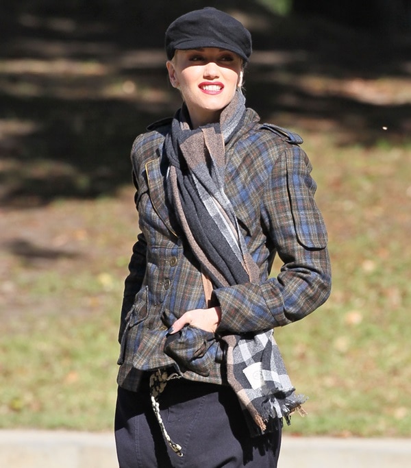Gwen Stefani exudes effortless style in a L.A.M.B. military plaid blazer, pairing it with a cozy striped scarf and a chic newsboy cap for a polished yet functional fall look