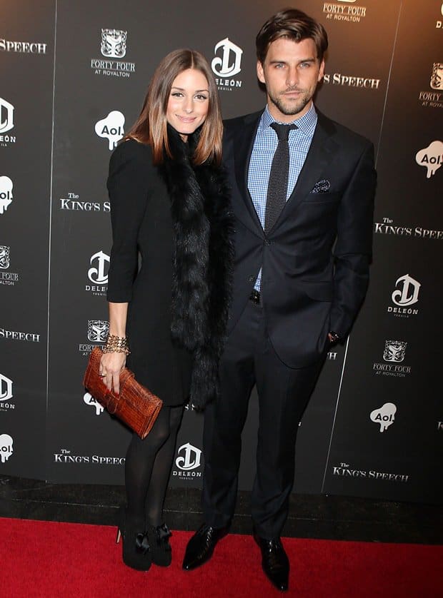 Olivia Palermo, alongside Johannes Huebl, exudes elegance at The King's Speech premiere in New York City, pairing her chic black ensemble with a luxe fur scarf and statement bow-adorned pumps for a refined red carpet look