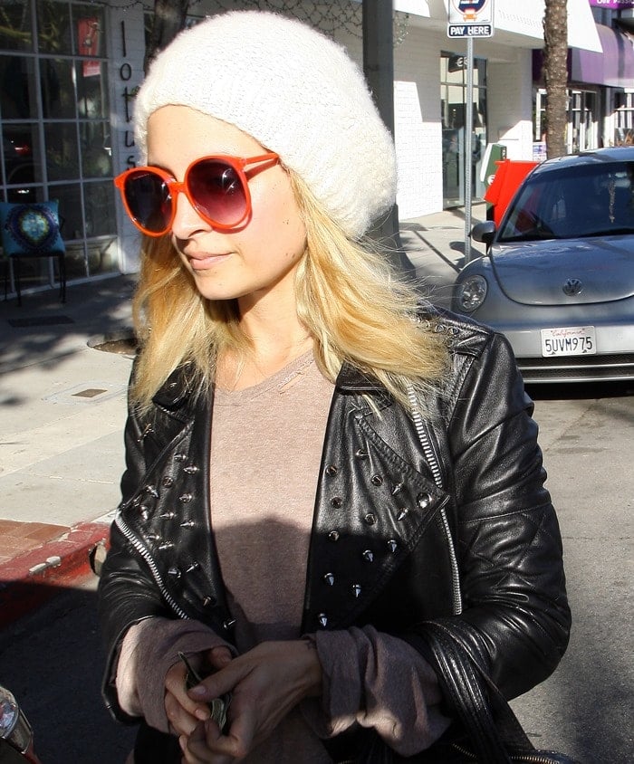 Fashion-forward Nicole Richie captivates with vibrant retro red sunglasses and a chic beanie, effortlessly elevating gym style