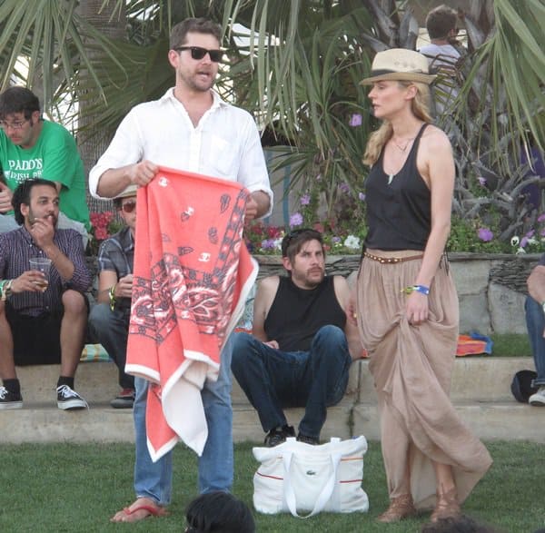 Diane Kruger embraces effortless festival style at Coachella in a flowy pleated maxi skirt, strappy flat sandals, a relaxed tank top, and a chic fedora for a boho-cool vibe