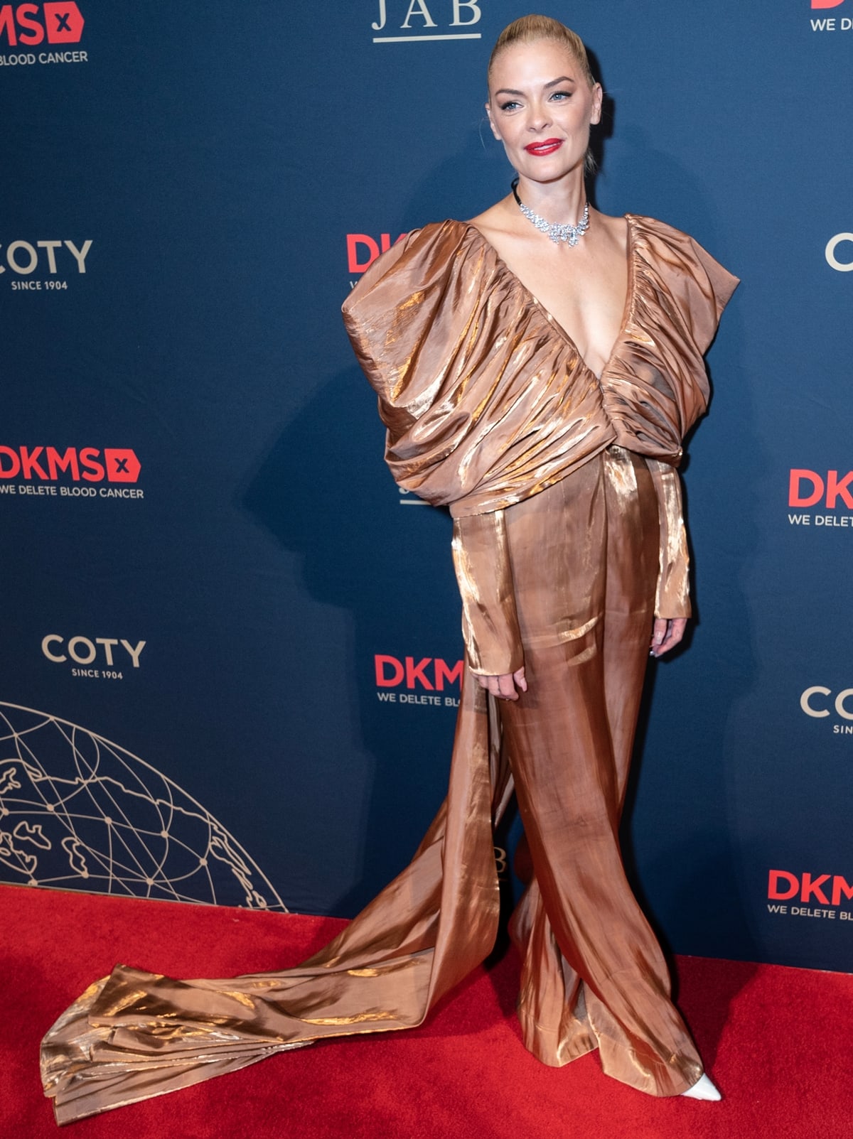 At the 2022 DKMS Gala in New York City on October 20, Jaime King, standing at 5 feet 8 inches (172.7 cm), dazzled in a gold Jovana Louis jumpsuit with exaggerated sleeves and a lustrous train, complemented by a diamond necklace with a black chain and a solid white leather clutch