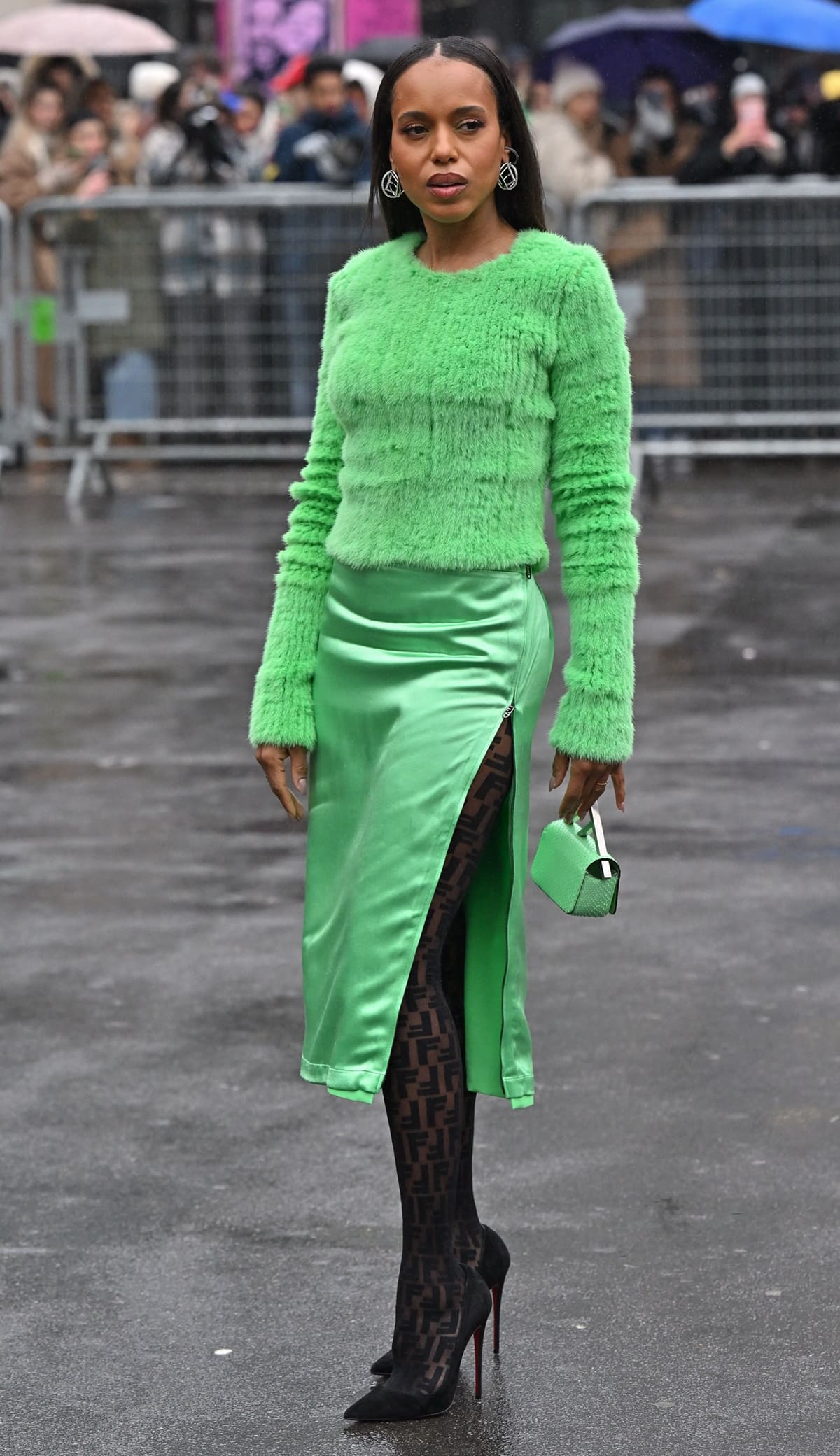 Kerry Washington wears a green outfit with black Fendi tights, large statement earrings, and a green mini bag for the Fendi Couture fashion show