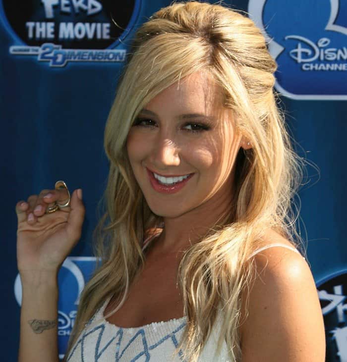 Ashley Tisdale styled her blonde waves in a half-up, half-down look, accessorizing with gold rings while showcasing her delicate wrist tattoo at the Phineas and Ferb: Across the 2nd Dimension premiere